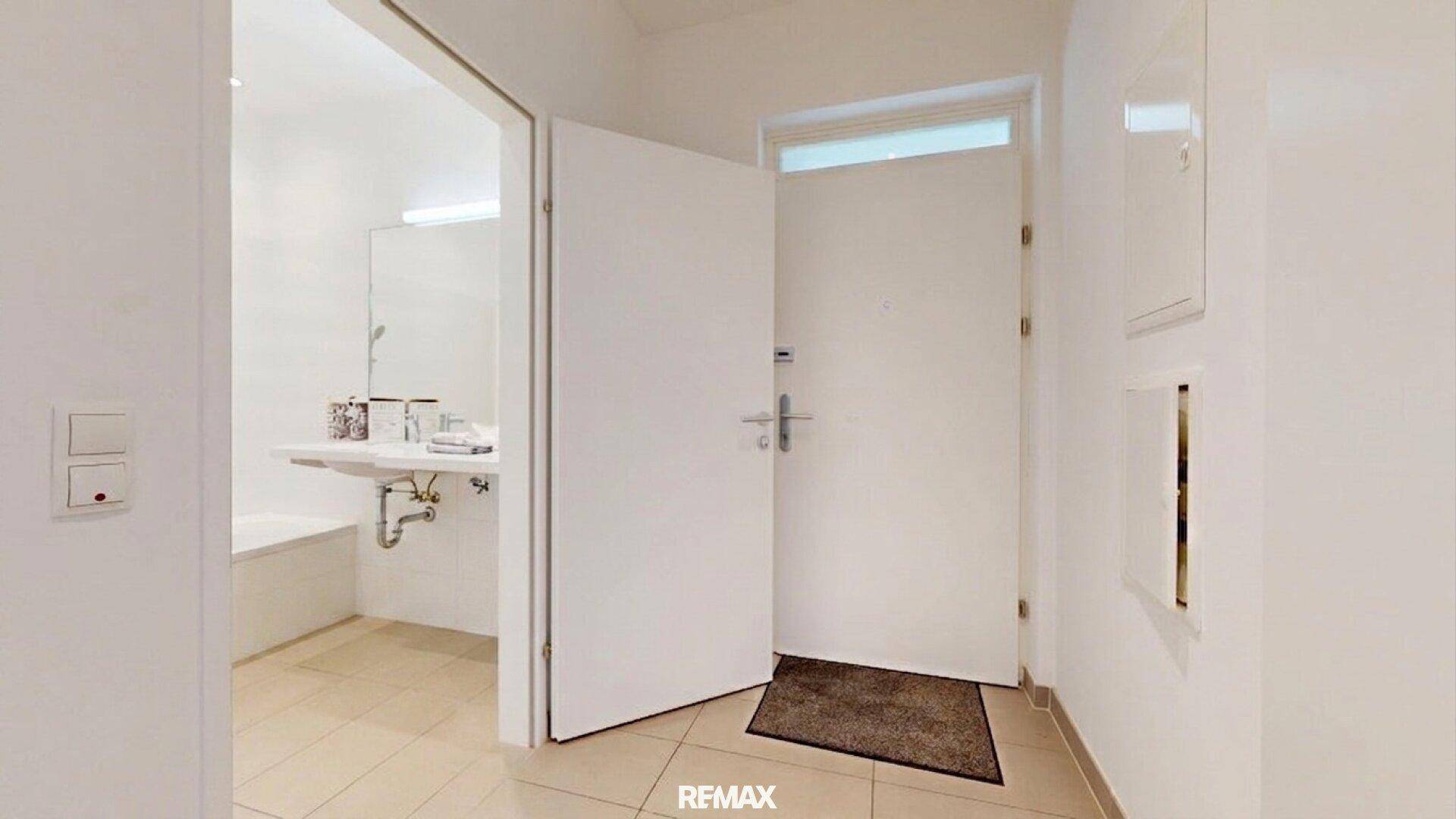 Eingangsbereich mit Fliesenboden und offenem Zugang zu einem Badezimmer.