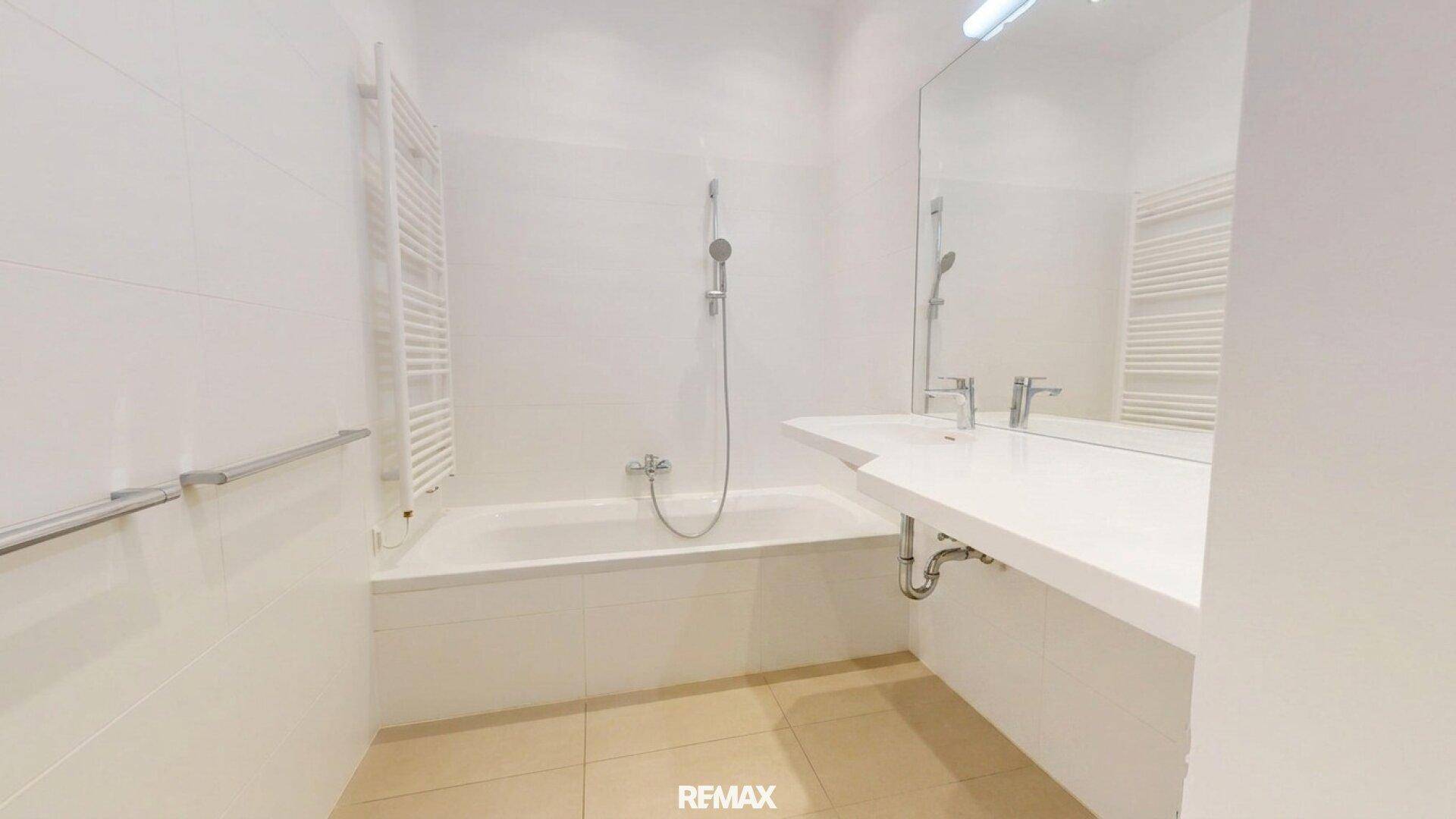Modernes Badezimmer mit Badewanne, Waschtisch und Handtuchheizkörper.
