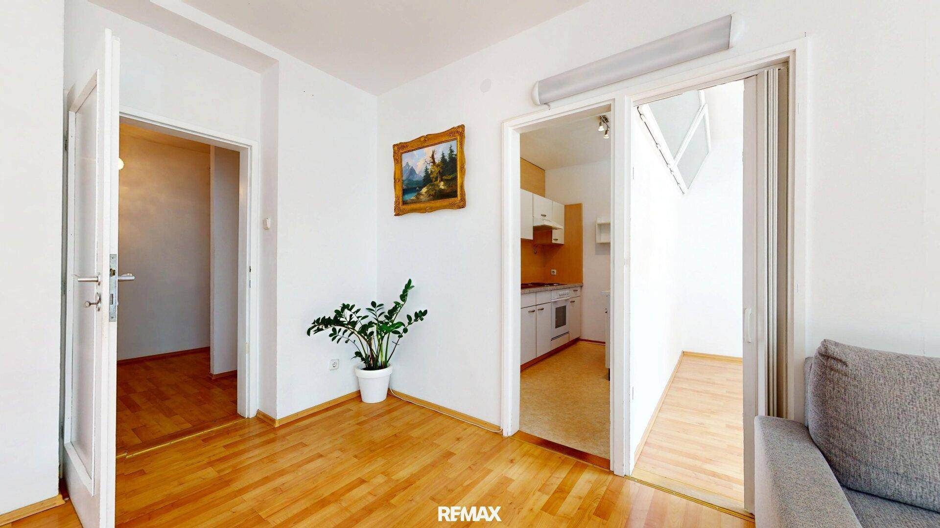 Wohnzimmer mit Zugang zu weiteren Räumen und einem Einblick in die angrenzende Küche.