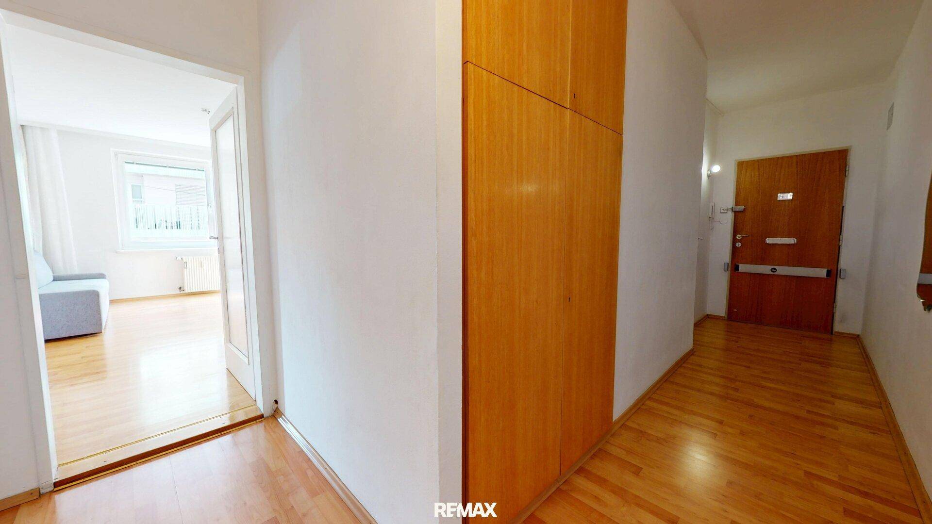 Eingangsbereich mit Holzparkett, integrierten Holzschränken und der Wohnungstür.