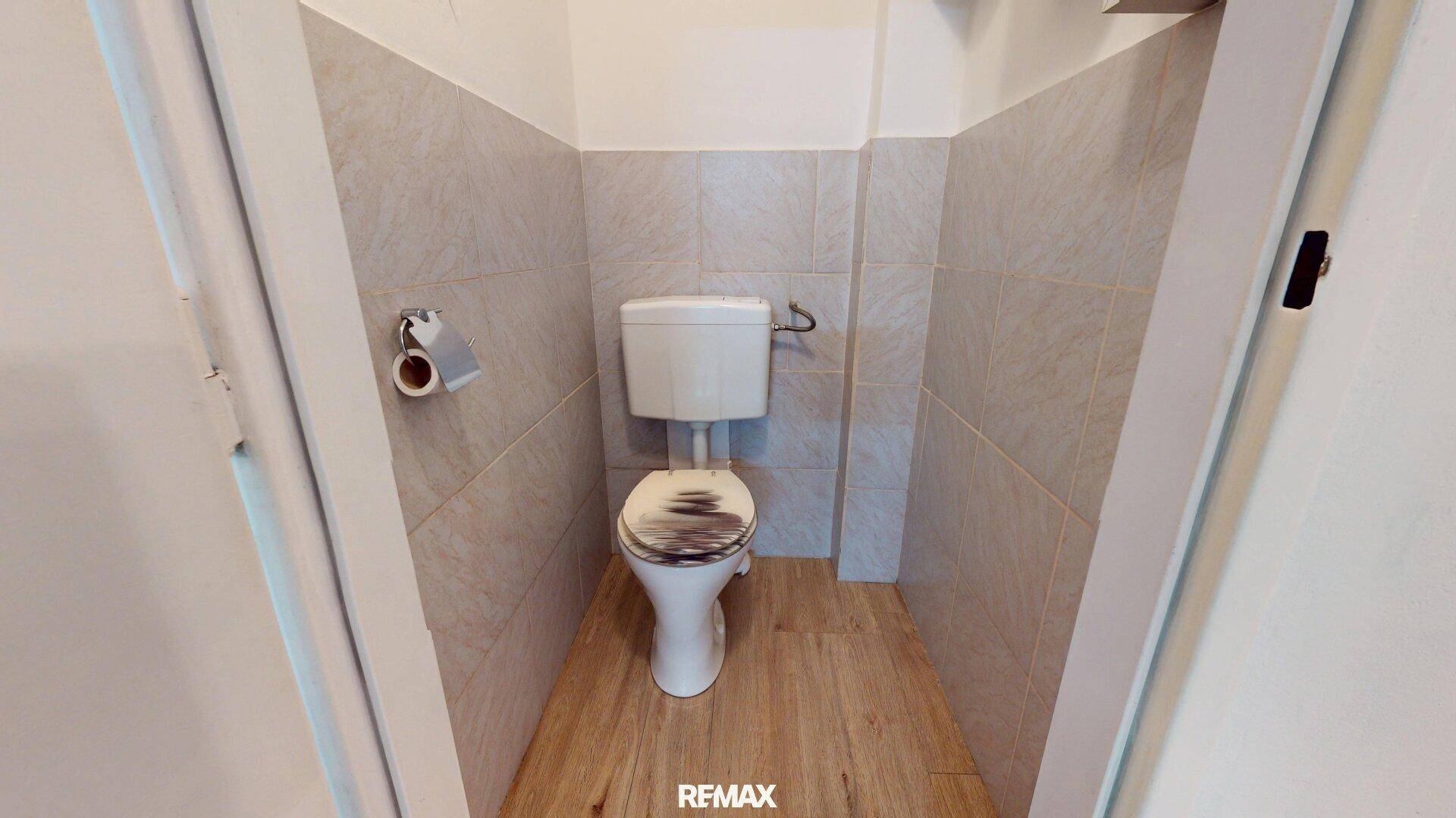 Separates WC mit Toilette und Fliesen an den Wänden.