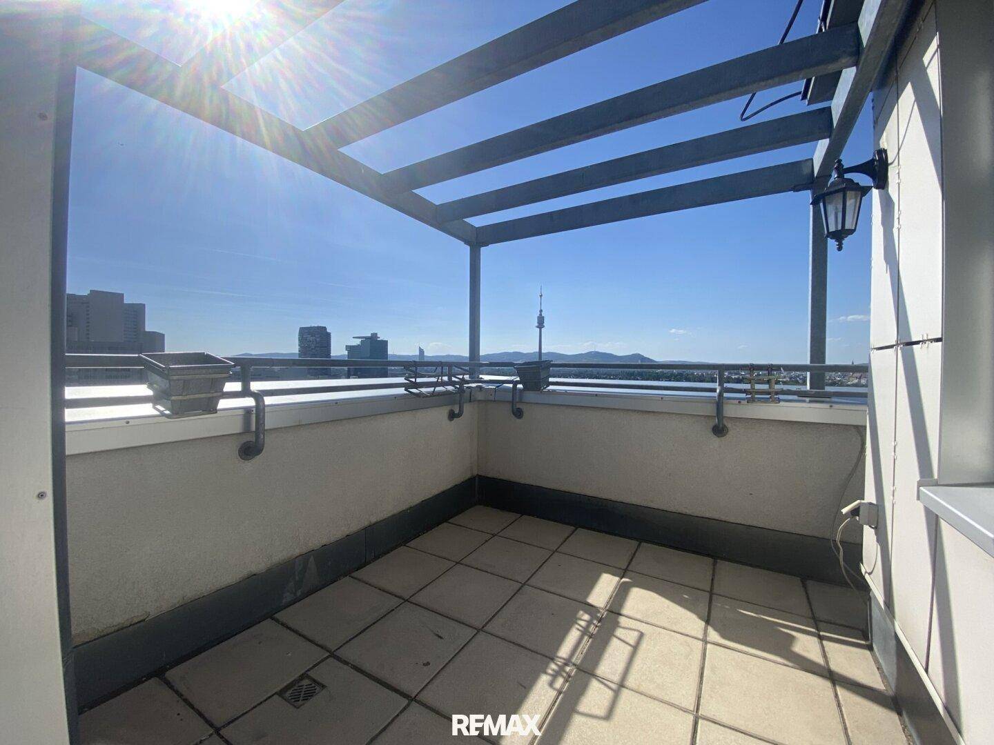 Sonnige Terrasse mit Fliesenboden und einer stabilen Pergola-Konstruktion für angenehme Stunden im Freien.