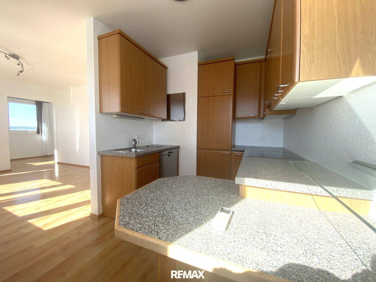 Praktische Küche mit Holzfronten und Granit-Arbeitsplatten, offen zum Wohnbereich gestaltet.