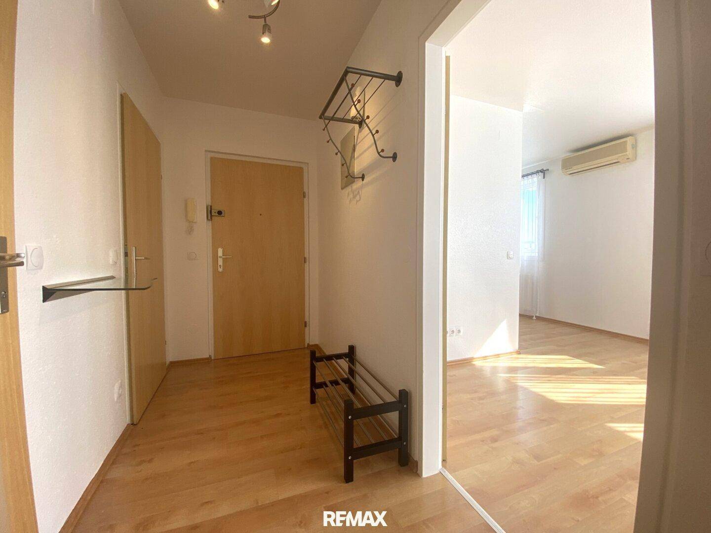 Freundlicher Eingangsbereich mit Holzboden, Garderobe und praktischer Schuhbank.
