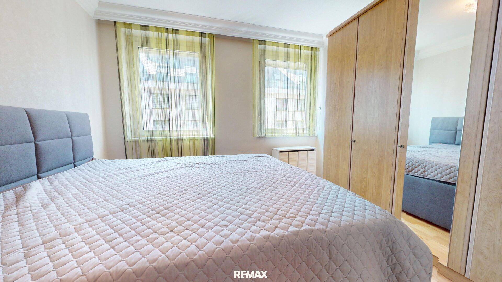 Schlafzimmer mit Doppelbett, Parkettboden und großem Kleiderschrank mit Spiegeltür.