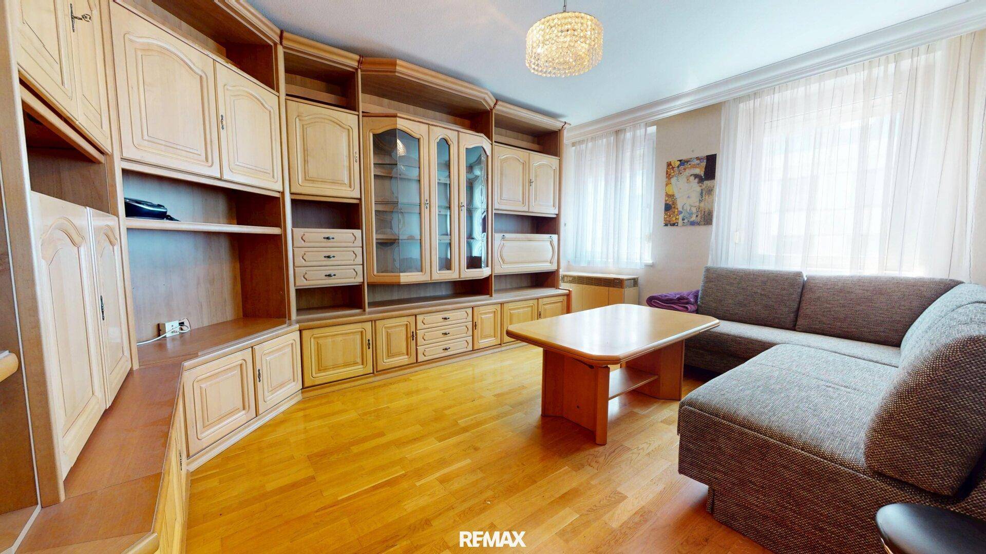 Gemütliches Wohnzimmer mit traditionellen Holzmöbeln, Sofa und Parkettboden.