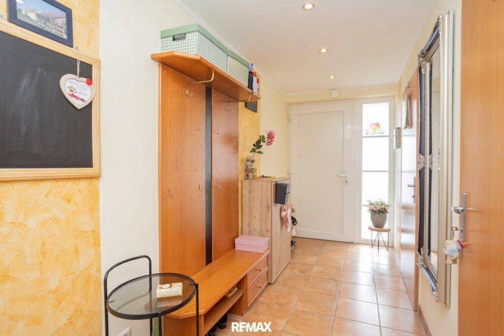Heller Eingangsbereich mit Garderobe, Spiegel und Fliesenboden, führt zur Haustür.