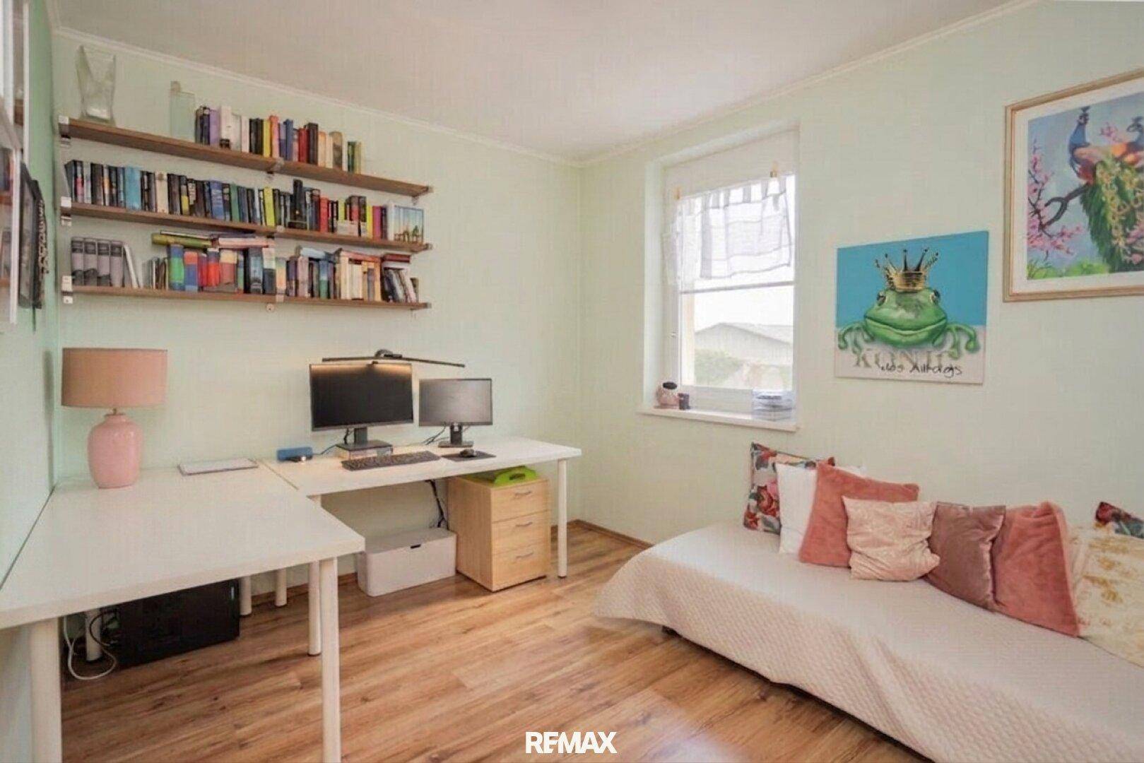 Helles Arbeitszimmer mit Schreibtisch, Bücherregalen und einem Tagesbett, ideal für Home-Office.