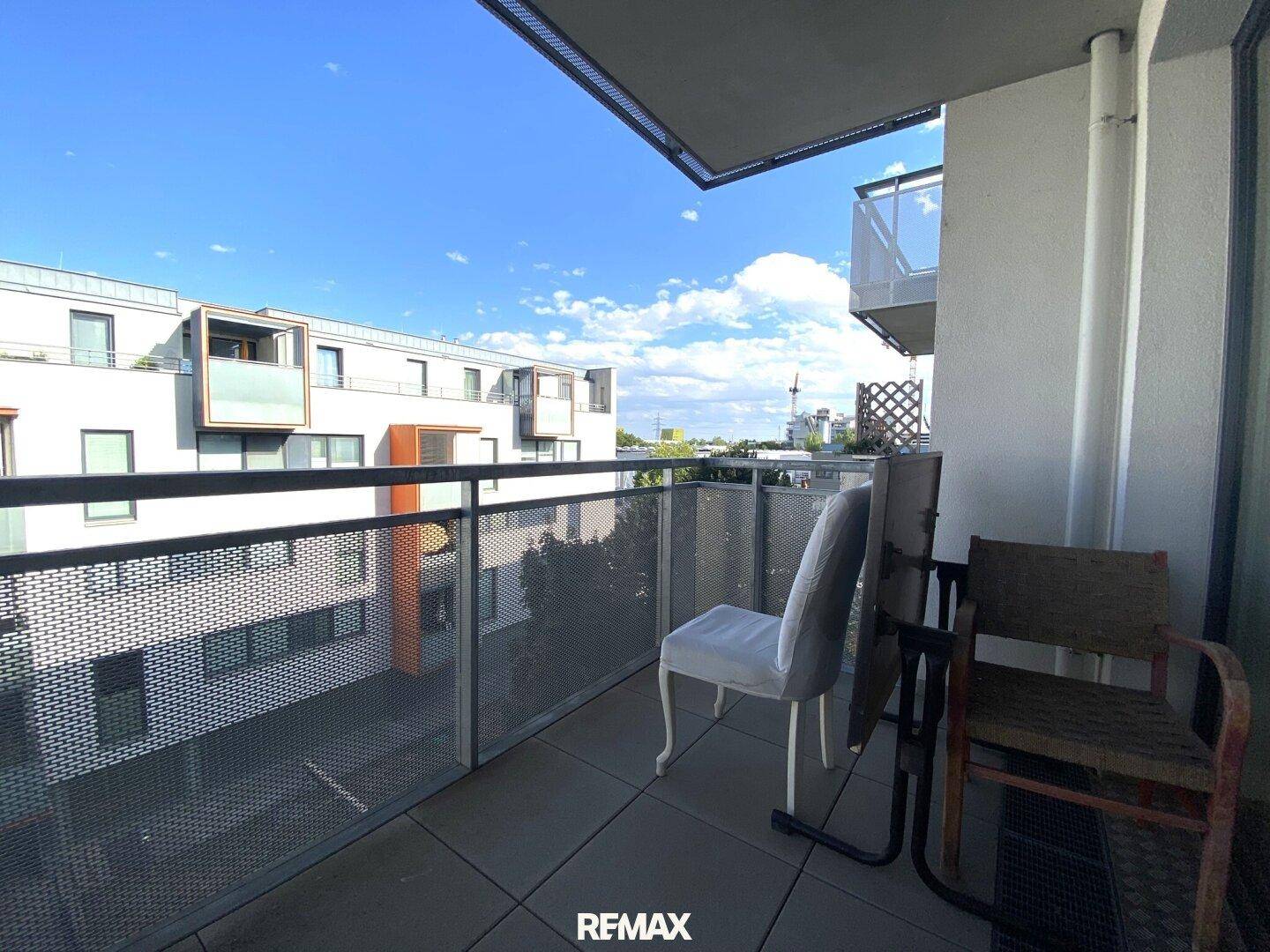 Heller Balkon mit Sitzgelegenheiten und Weitblick über die Nachbarschaft.