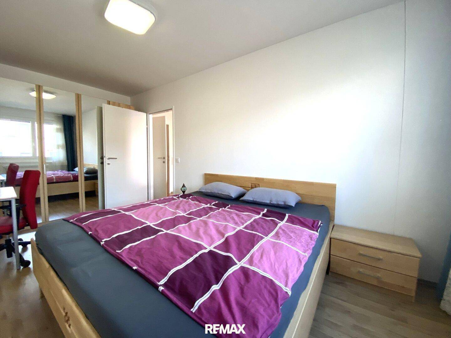 Helles Schlafzimmer mit Holzboden, großem Bett und Spiegelschränken.
