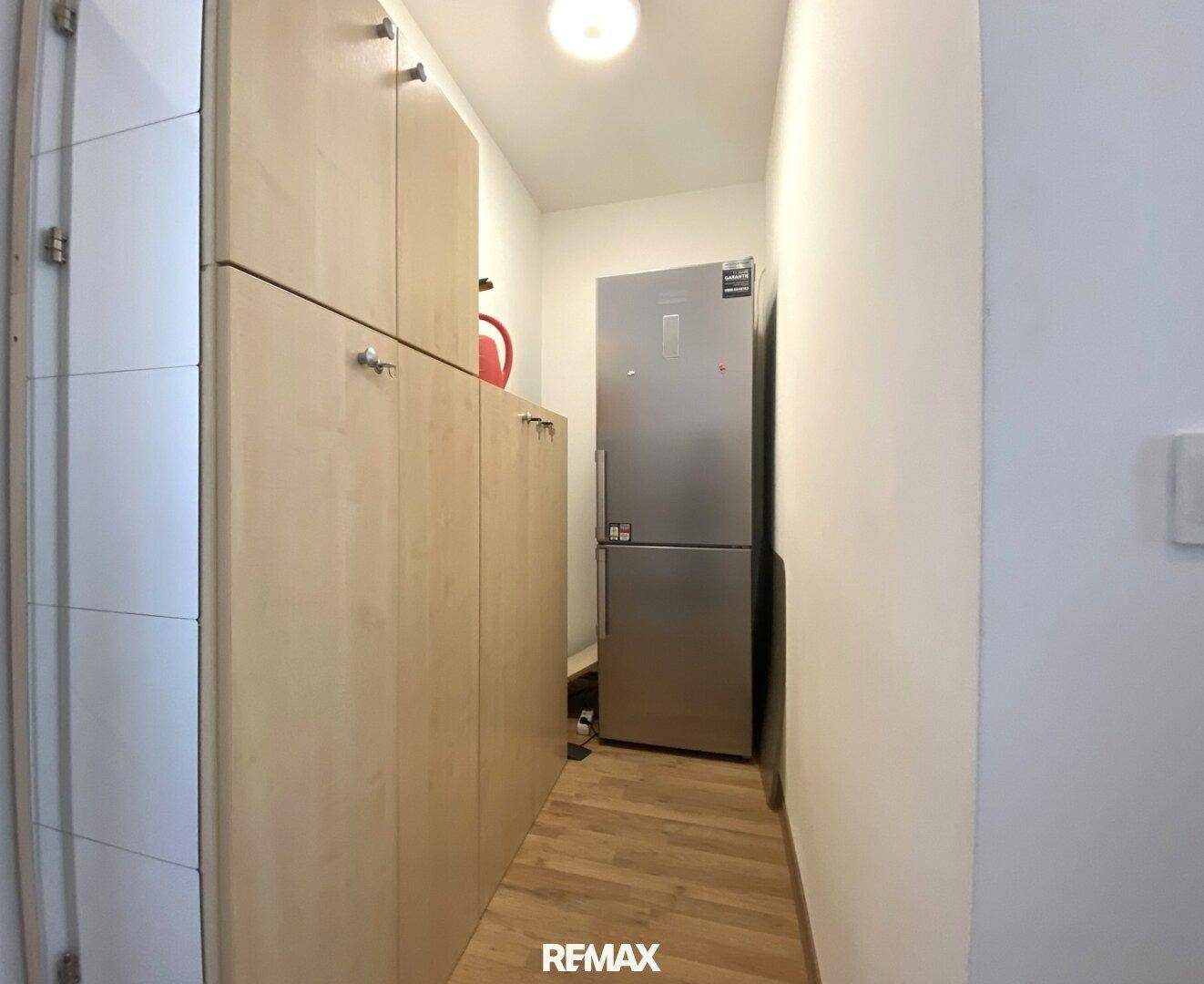 Praktischer Abstellraum mit Einbauschränken und Kühlschrank.