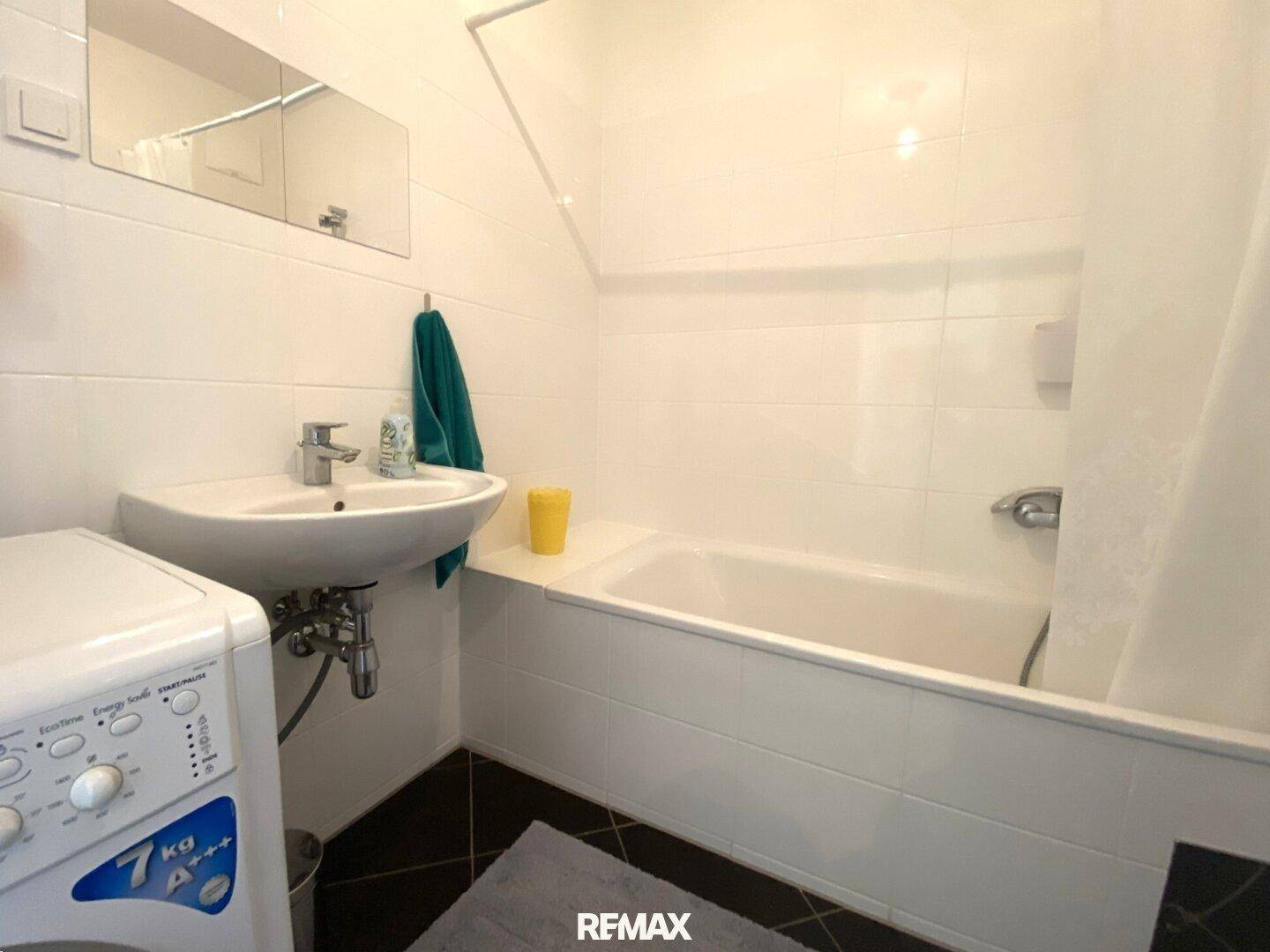 Badezimmer mit Badewanne, Waschbecken und Waschmaschine.