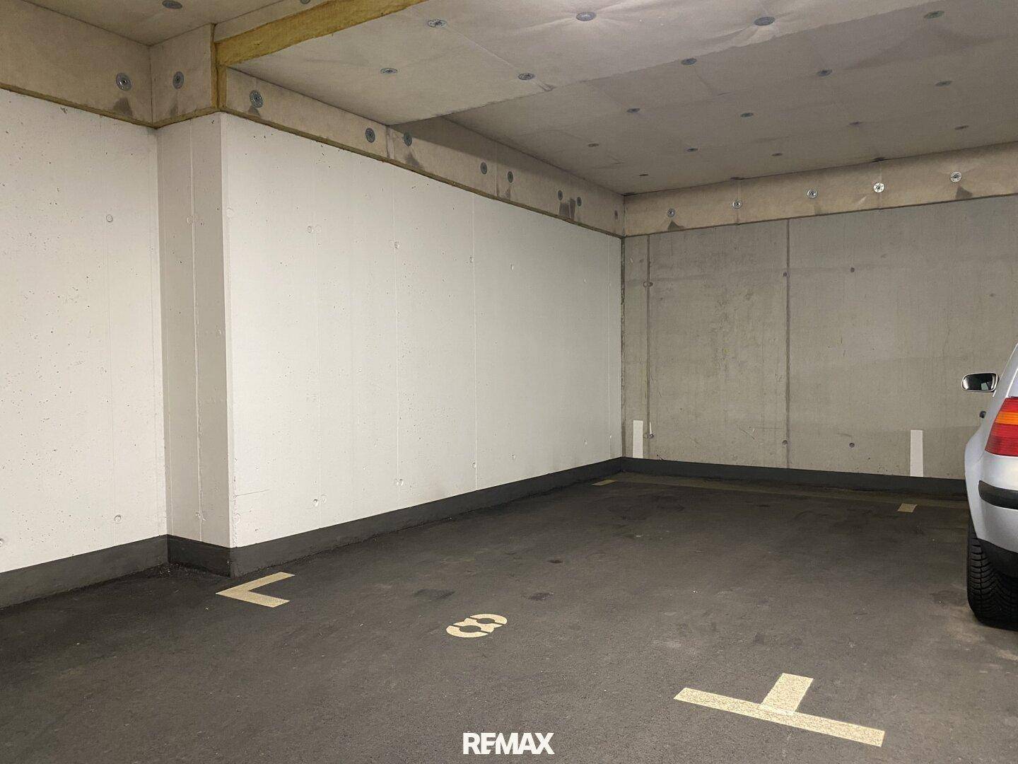 Einzelner Stellplatz in der Tiefgarage mit Betonwänden.