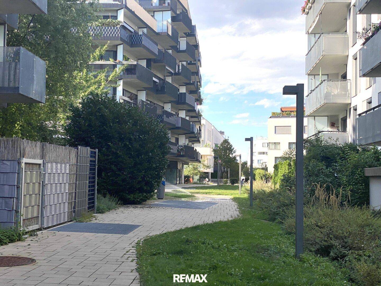 Gepflegte Grünanlage zwischen modernen Wohngebäuden mit Gehwegen.