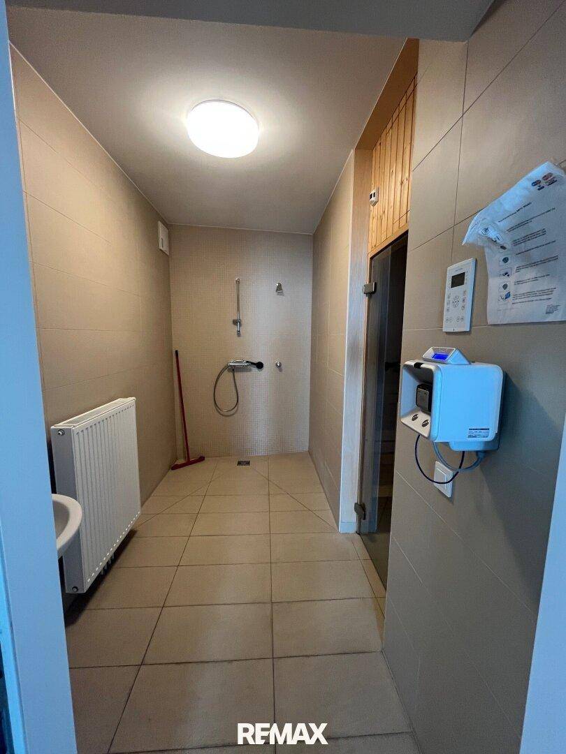 Duschbereich in einem Wellnessbereich mit Fliesenboden und Heizkörper.