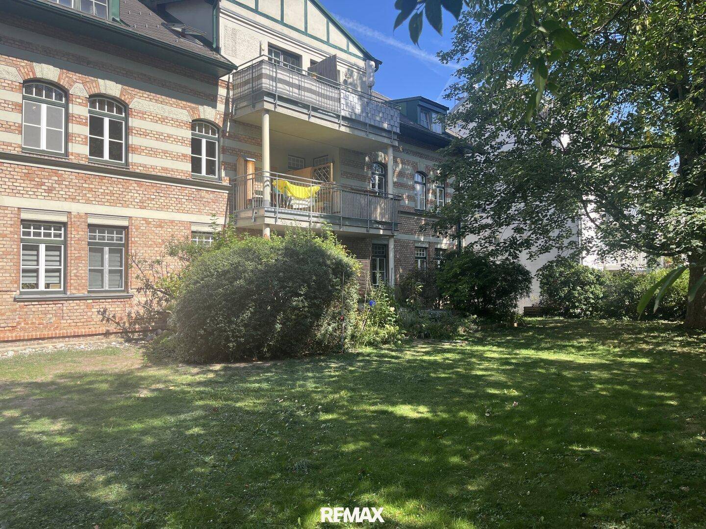 Weitläufiger Garten mit Rasenfläche und Blick auf die historische Gebäudefassade.