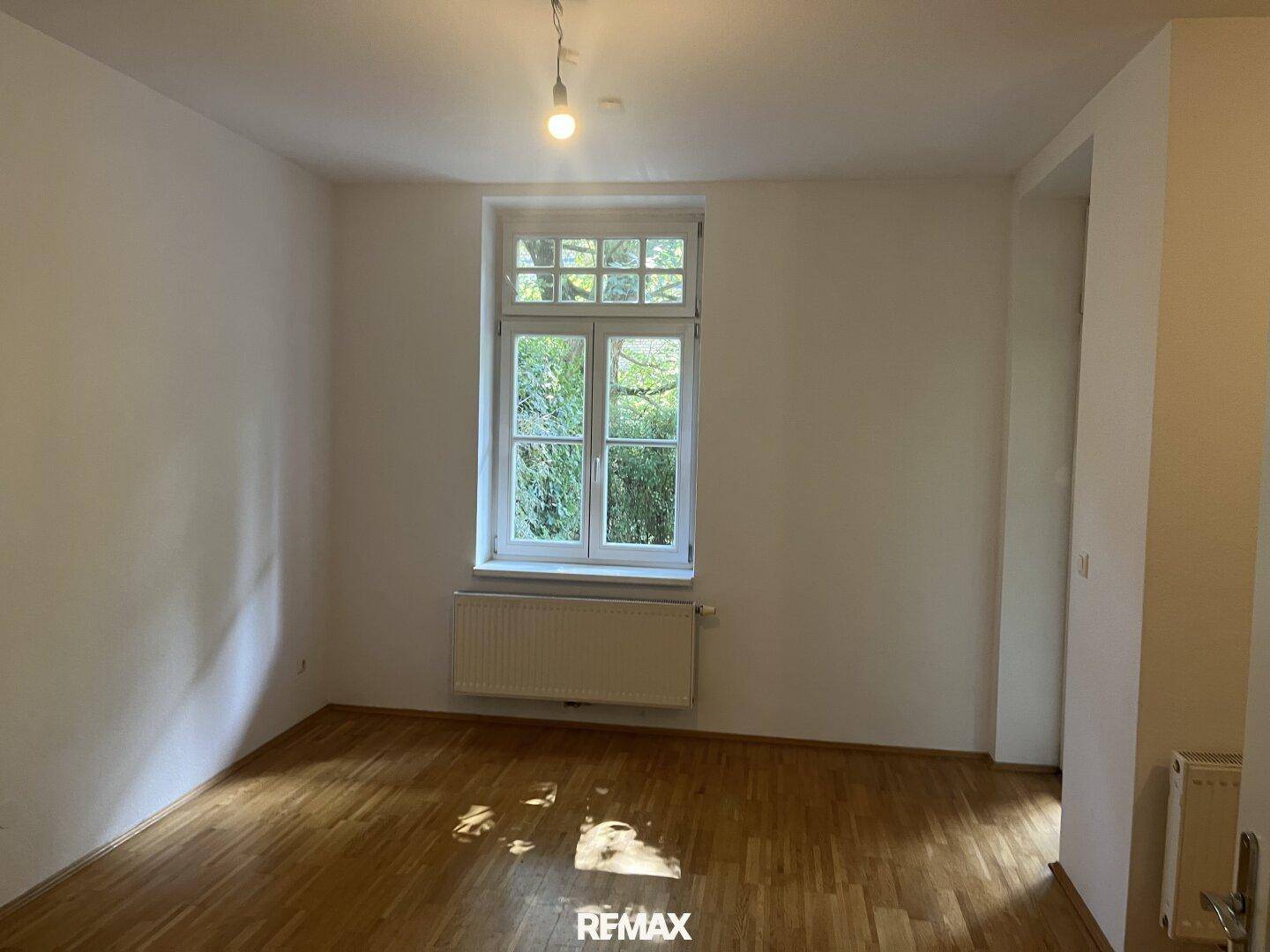 Ruhiges Schlafzimmer mit Parkettboden und großem Fenster zum Garten.