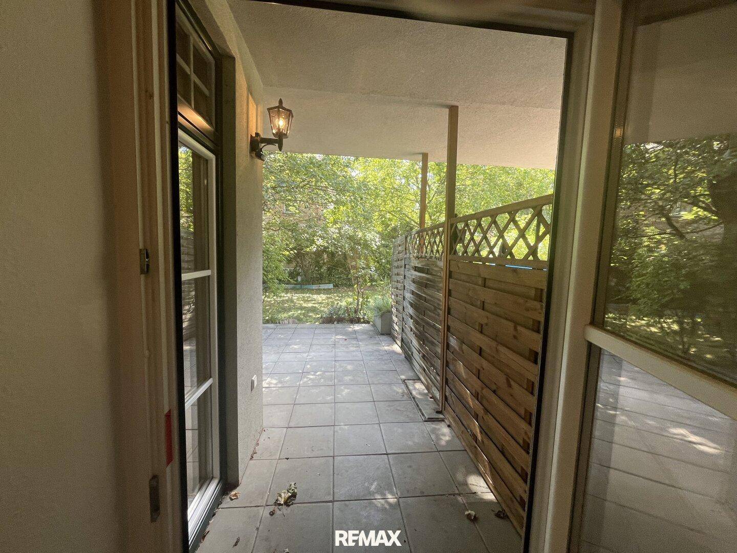 Blick vom Innenbereich auf die private Terrasse mit Holzsichtschutz.