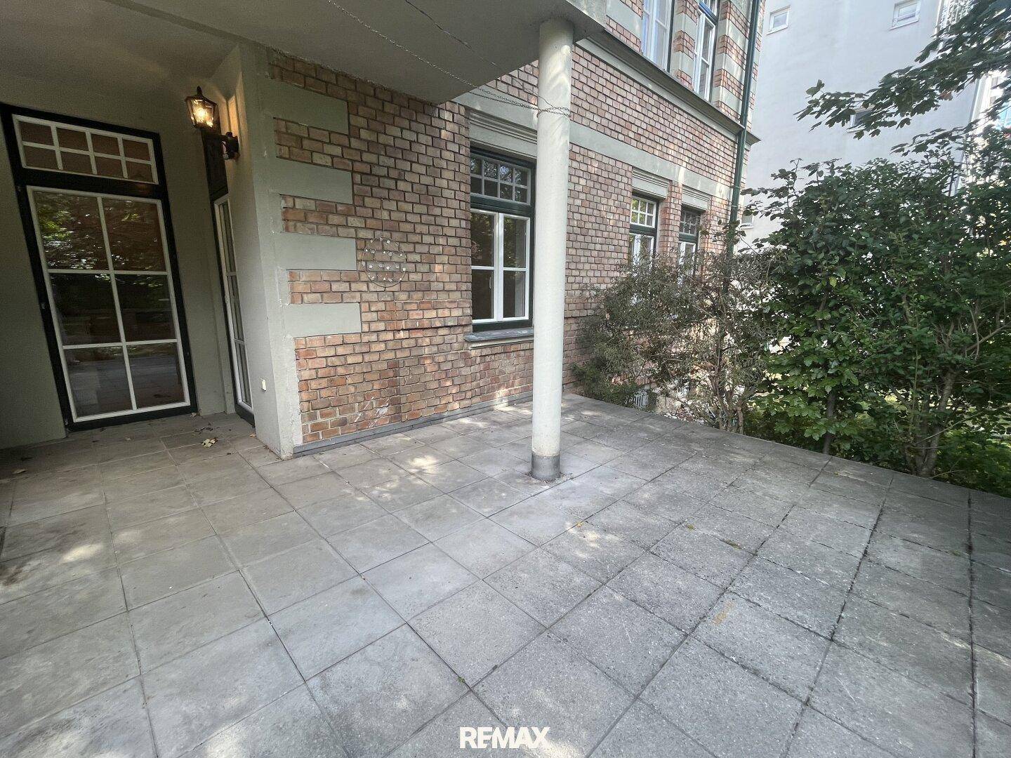 Geräumige, geflieste Terrasse mit Säule und direktem Zugang zum Gebäude.
