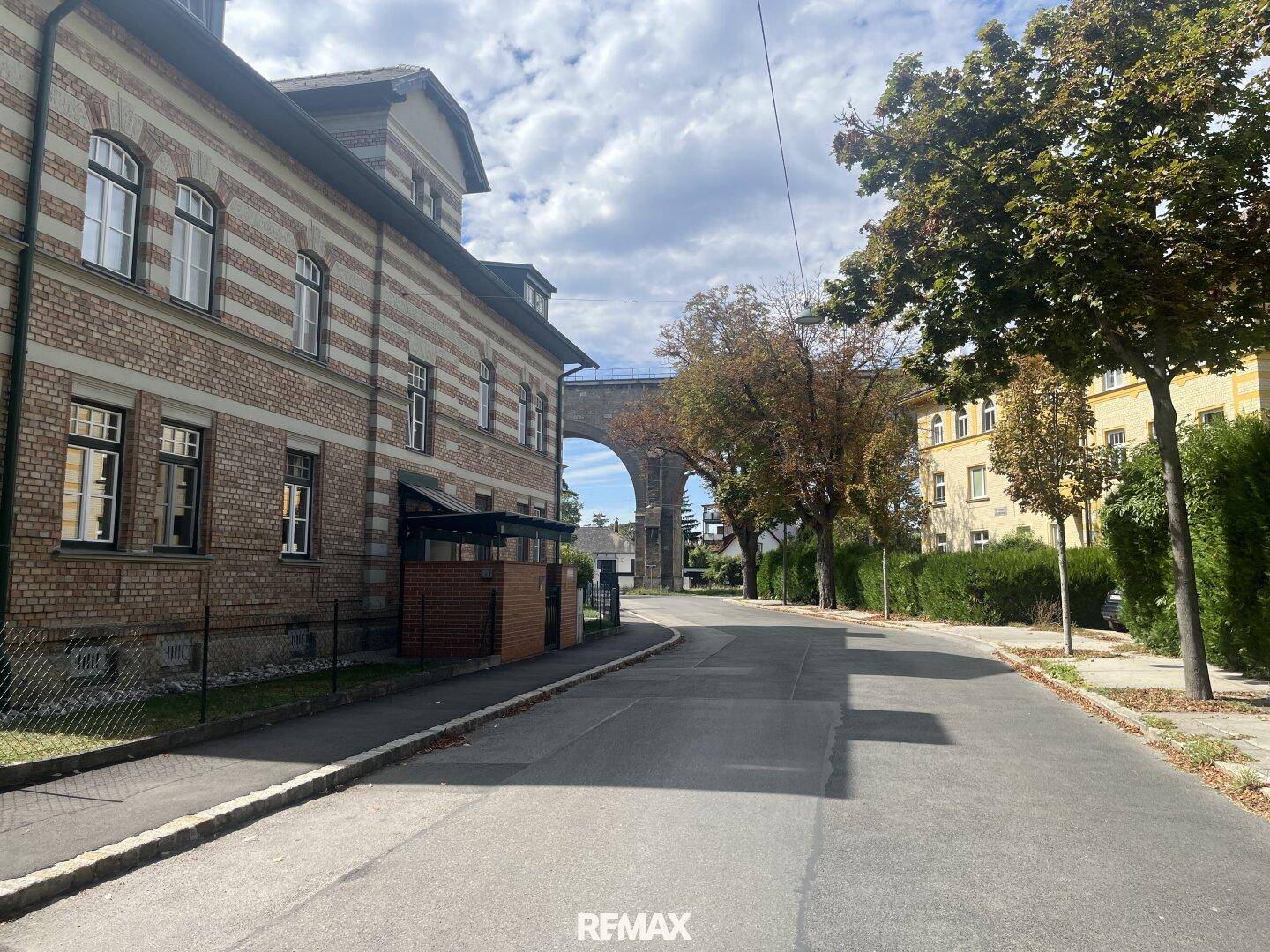 Historisches Backsteingebäude an einer ruhigen Straße mit Blick auf das imposante Viadukt.