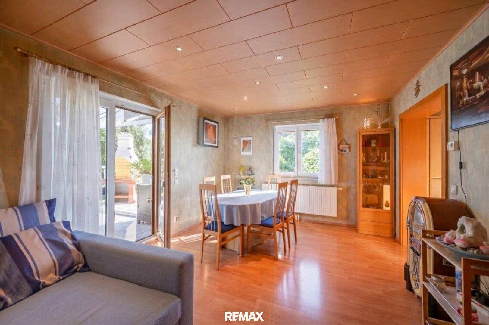 Heller Wohn- und Essbereich mit Holzboden und Zugang zur überdachten Terrasse.
