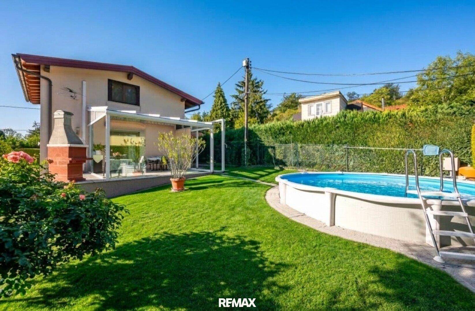Großer grüner Gartenbereich mit einem Aufstellpool und einer überdachten Terrasse am Haus.