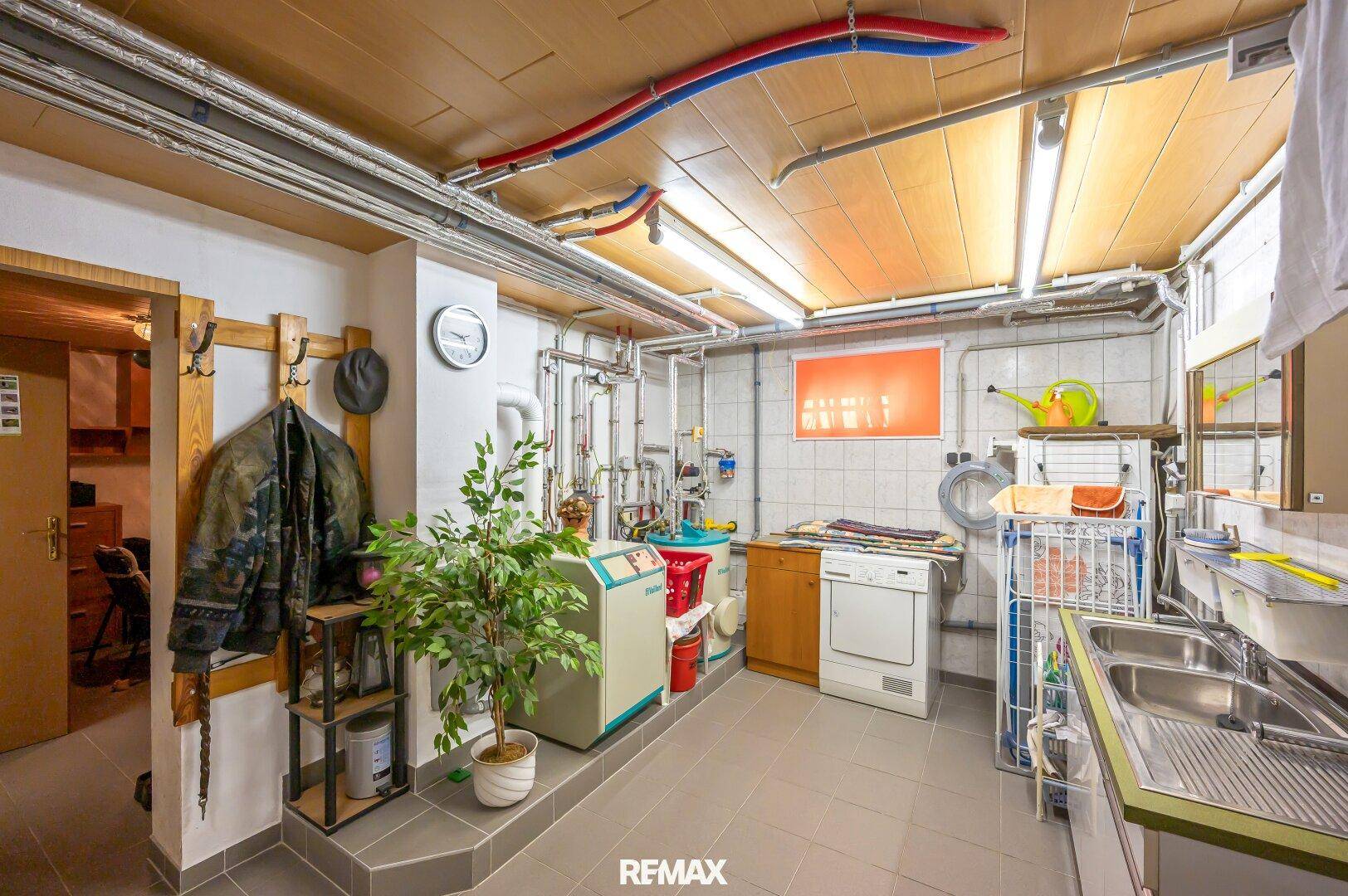 Geräumiger Hauswirtschaftsraum im Keller mit Waschmaschine, Spüle und Heizungsanlage.