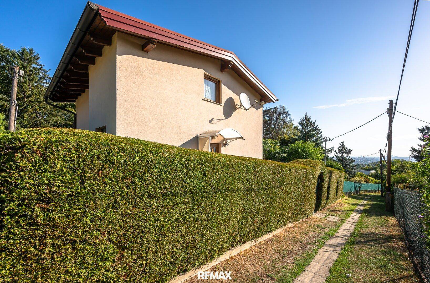 Ansicht des Hauses von der Seite, umgeben von einer hohen Hecke.