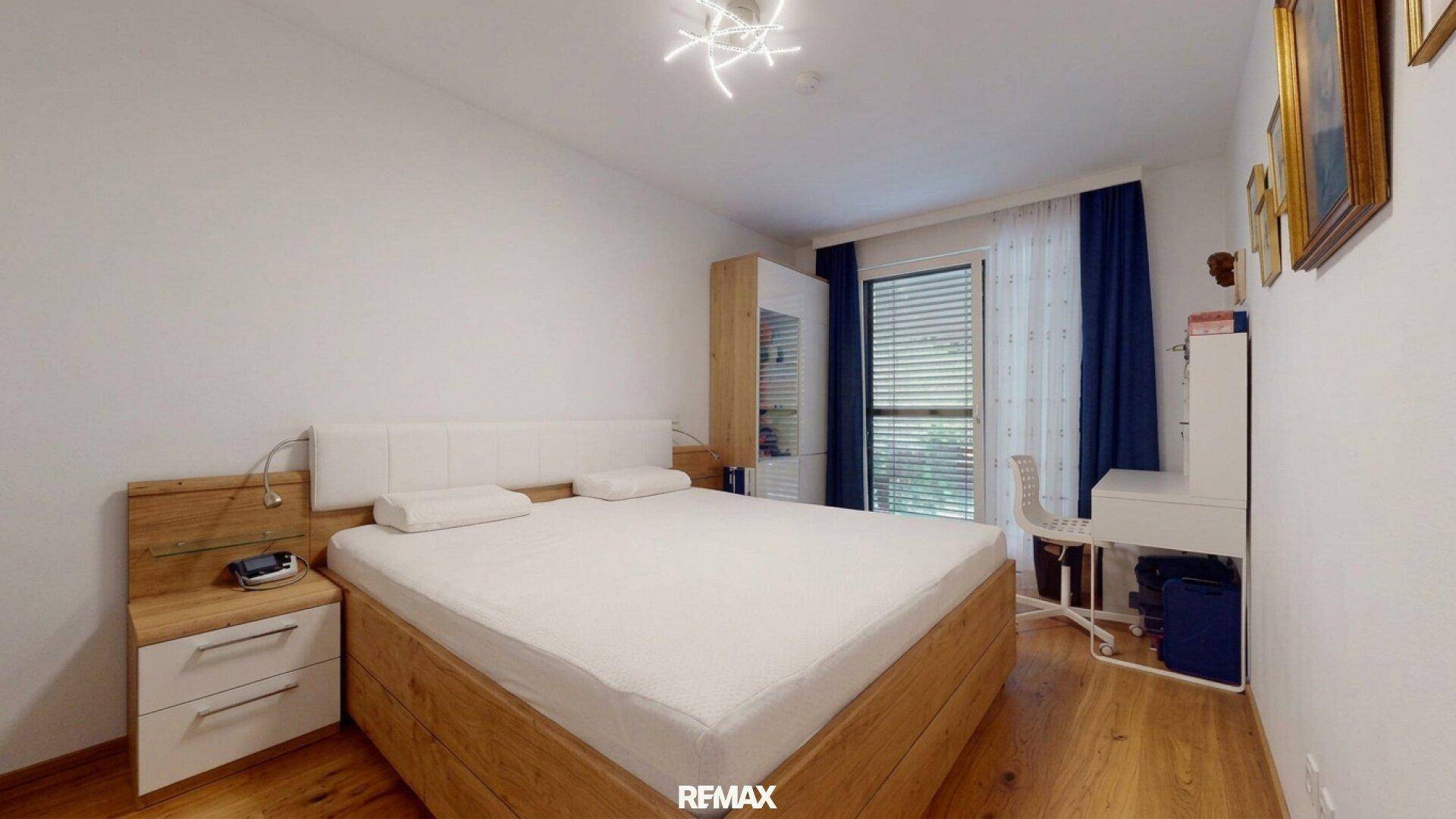 Gemütliches Schlafzimmer mit Holzbett, Nachttischen und großem Fenster für viel Licht.