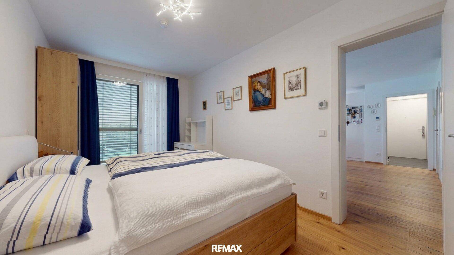 Schlafzimmer mit Holzboden, Doppelbett und direktem Zugang zum Flur.