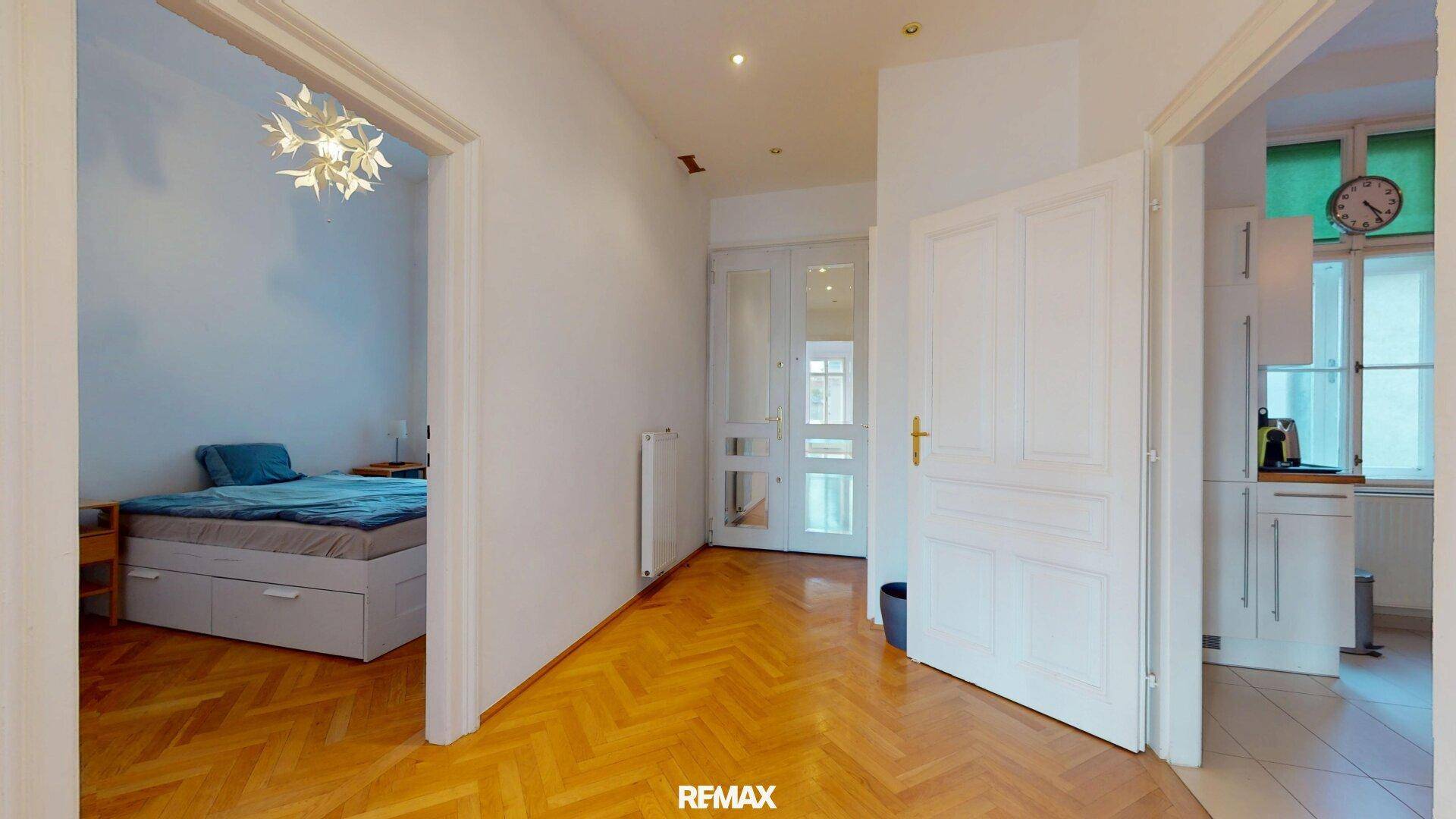 Flur mit Fischgrätparkett, der zu Schlafzimmer und Küche führt.