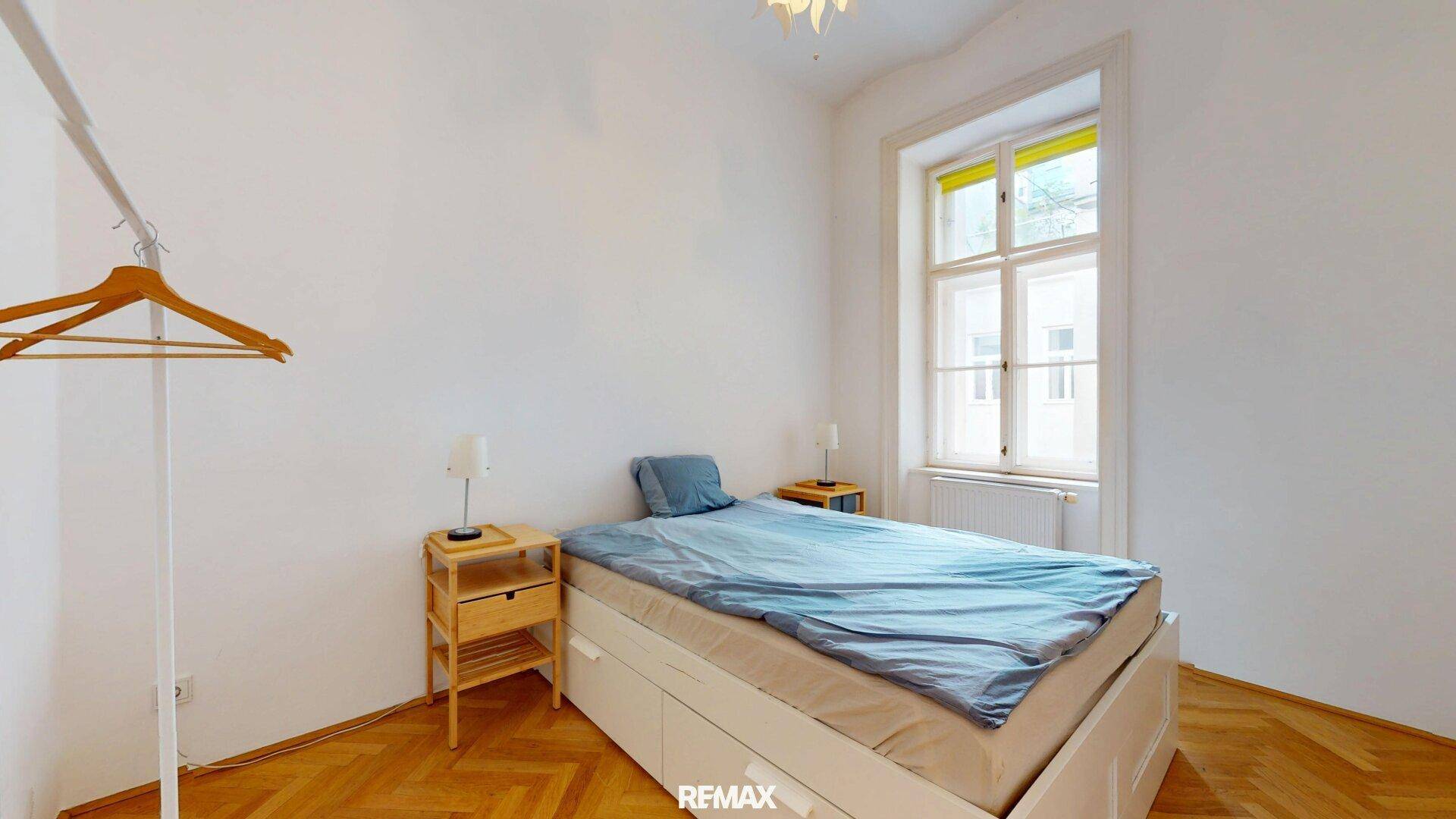 Schlafzimmer mit Einzelbett, Nachttischen und großem Fenster für viel Tageslicht.