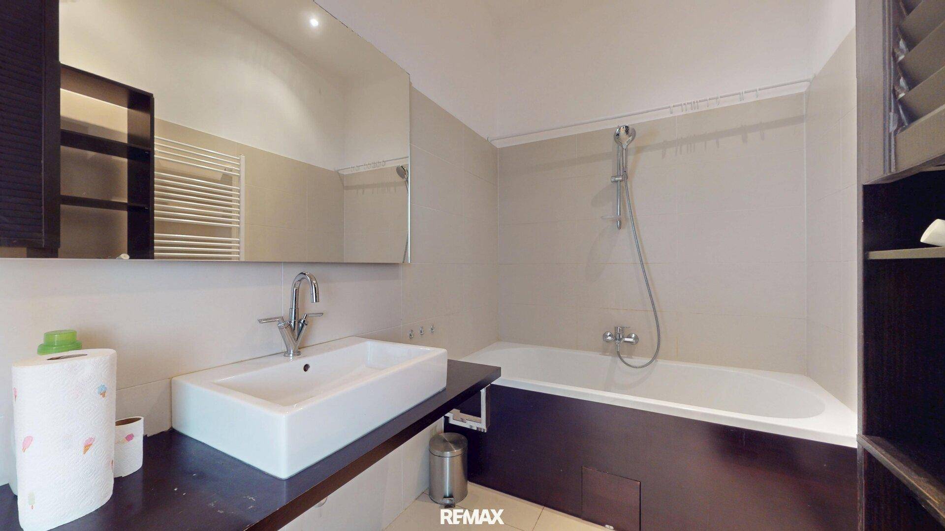 Modernes Badezimmer mit Badewanne, Waschtisch und beheiztem Handtuchhalter.