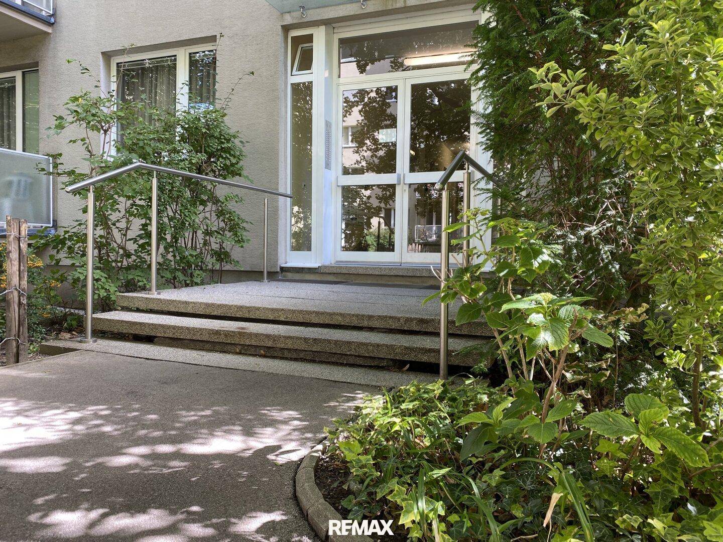 Eingangsbereich des Gebäudes mit Rampe und Handlauf für Barrierefreiheit.