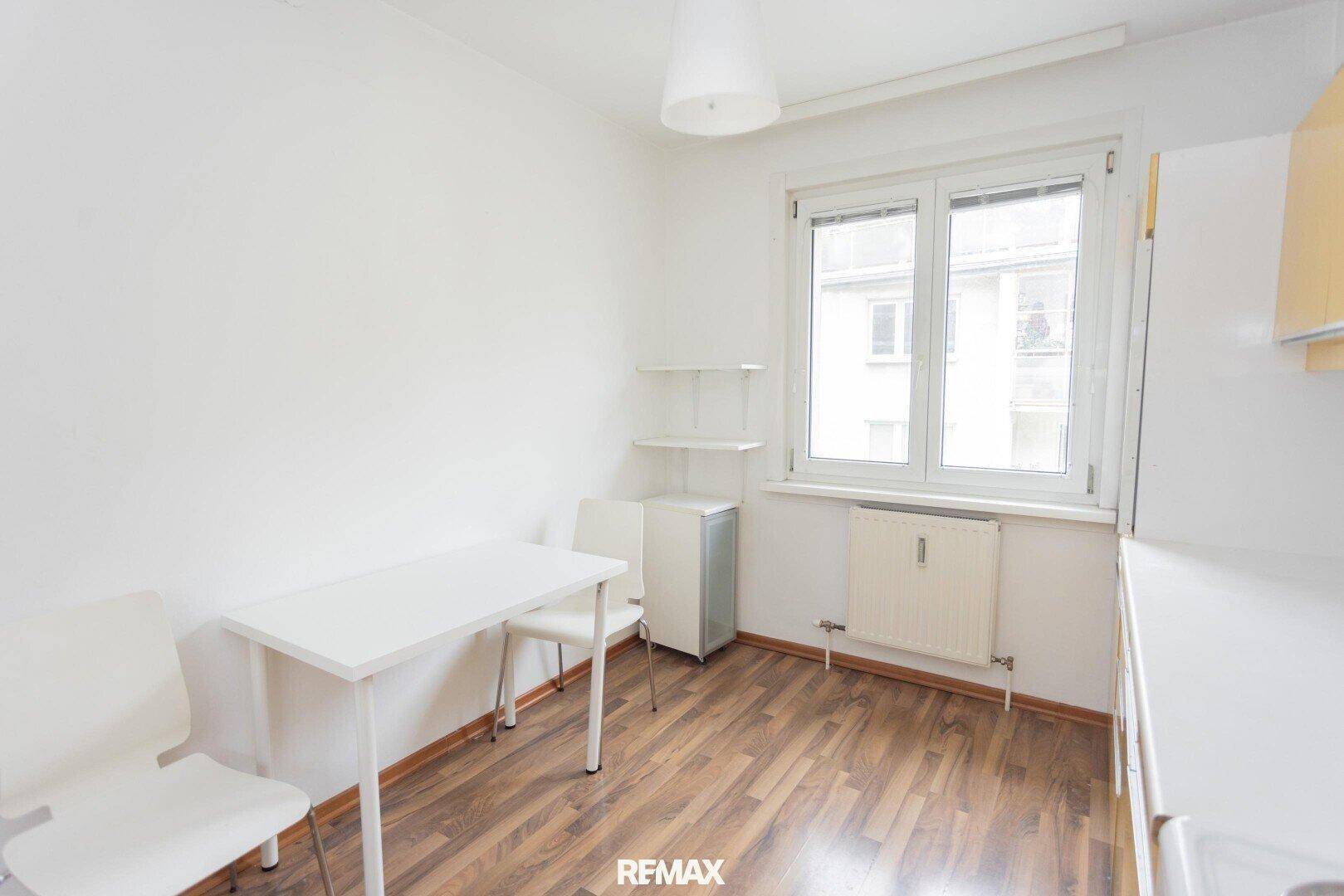 Essbereich in der Küche mit kleinem Tisch und Stühlen, neben einem Fenster.