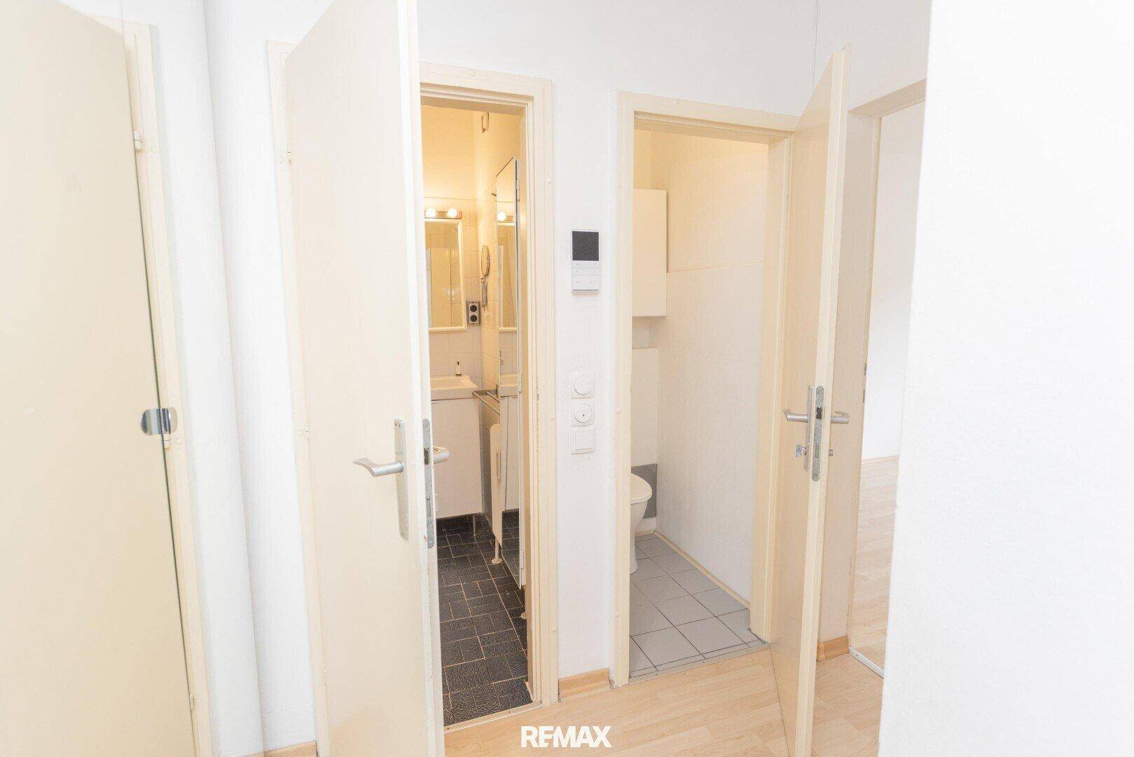 Flur mit offenen Türen zu einem Badezimmer und einer separaten Toilette.