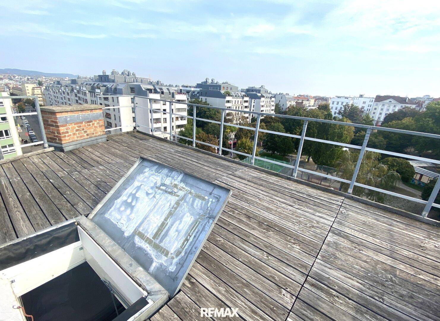 Geräumige Dachterrasse mit Holzboden, Zugang zum Innenbereich und weitem Blick über die Stadt.