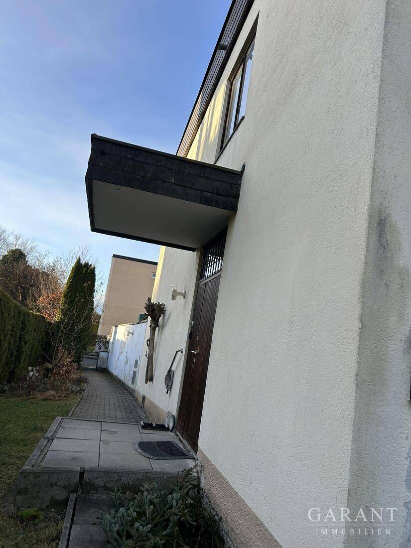 Seitenansicht des Gebäudes mit Eingangstür und einem kleinen Vordach.
