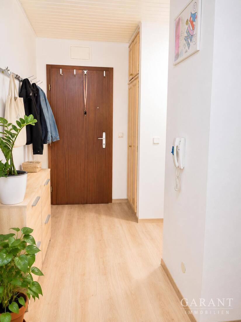 Heller Flur mit Laminatboden, Garderobe und Pflanzen, führt zu weiteren Räumen.
