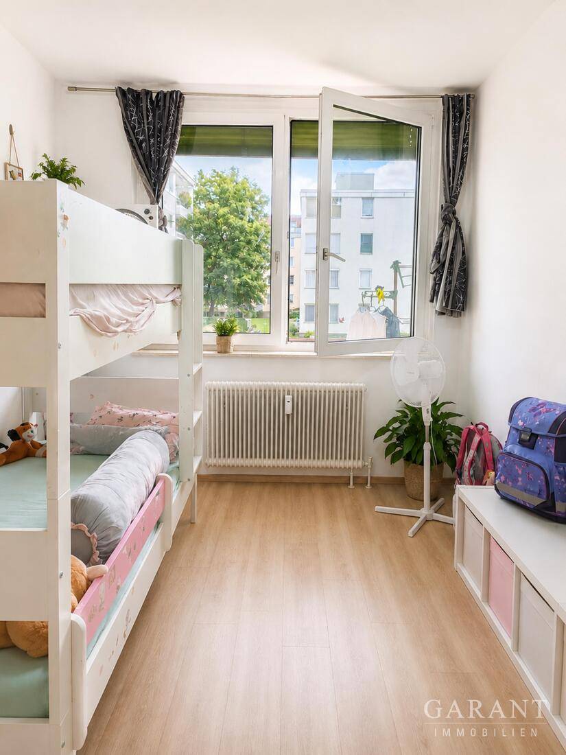 Kinderzimmer mit Etagenbett, hellem Laminatboden und großem Fenster mit Blick ins Grüne.
