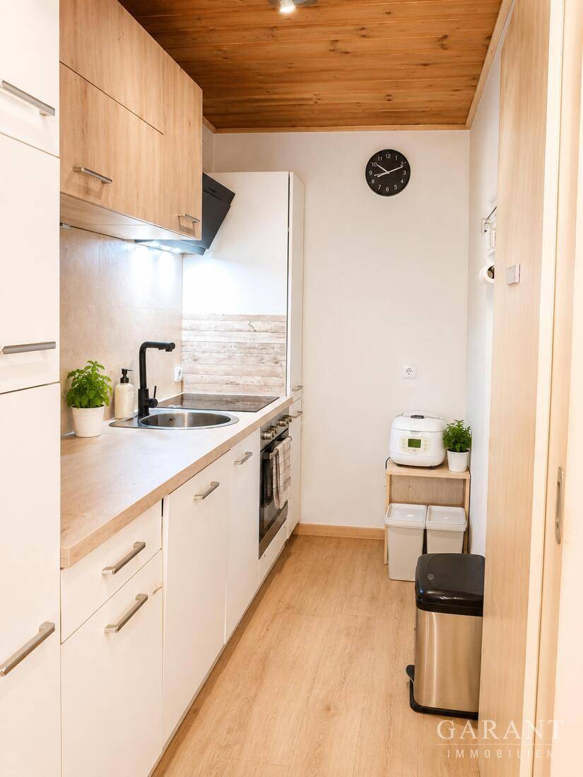 Schmale Küche mit hellen Holzschränken, Laminatboden und Holzdecke.