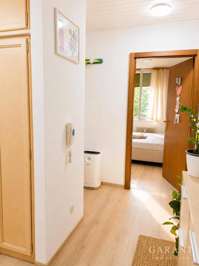 Flur mit Laminatboden und Blick in ein Schlafzimmer, ausgestattet mit einem Luftreiniger.