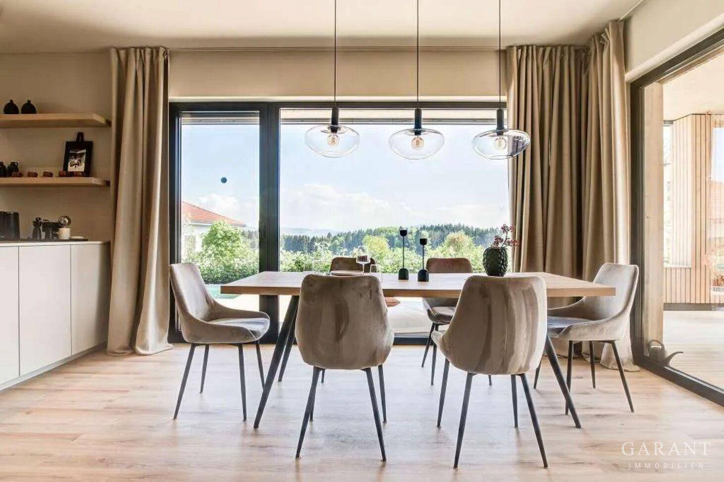 Eleganter Essbereich mit großen Fenstern, Holztisch und weitem Blick ins Grüne.