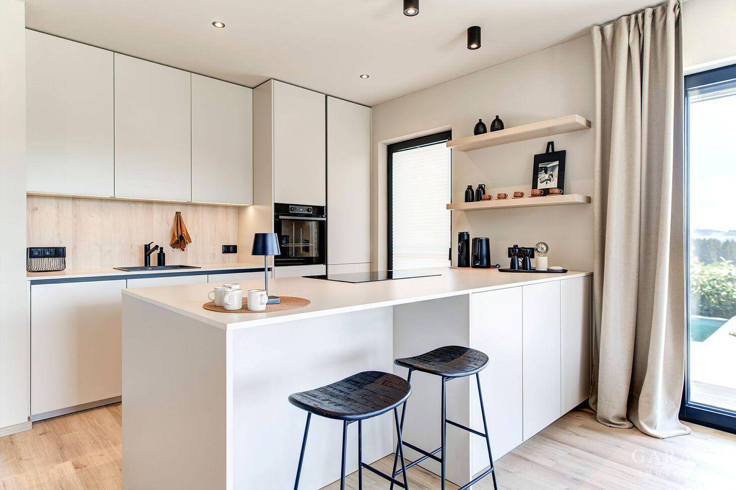Helle, moderne Küche mit Kücheninsel, integrierten Geräten und Holzboden.