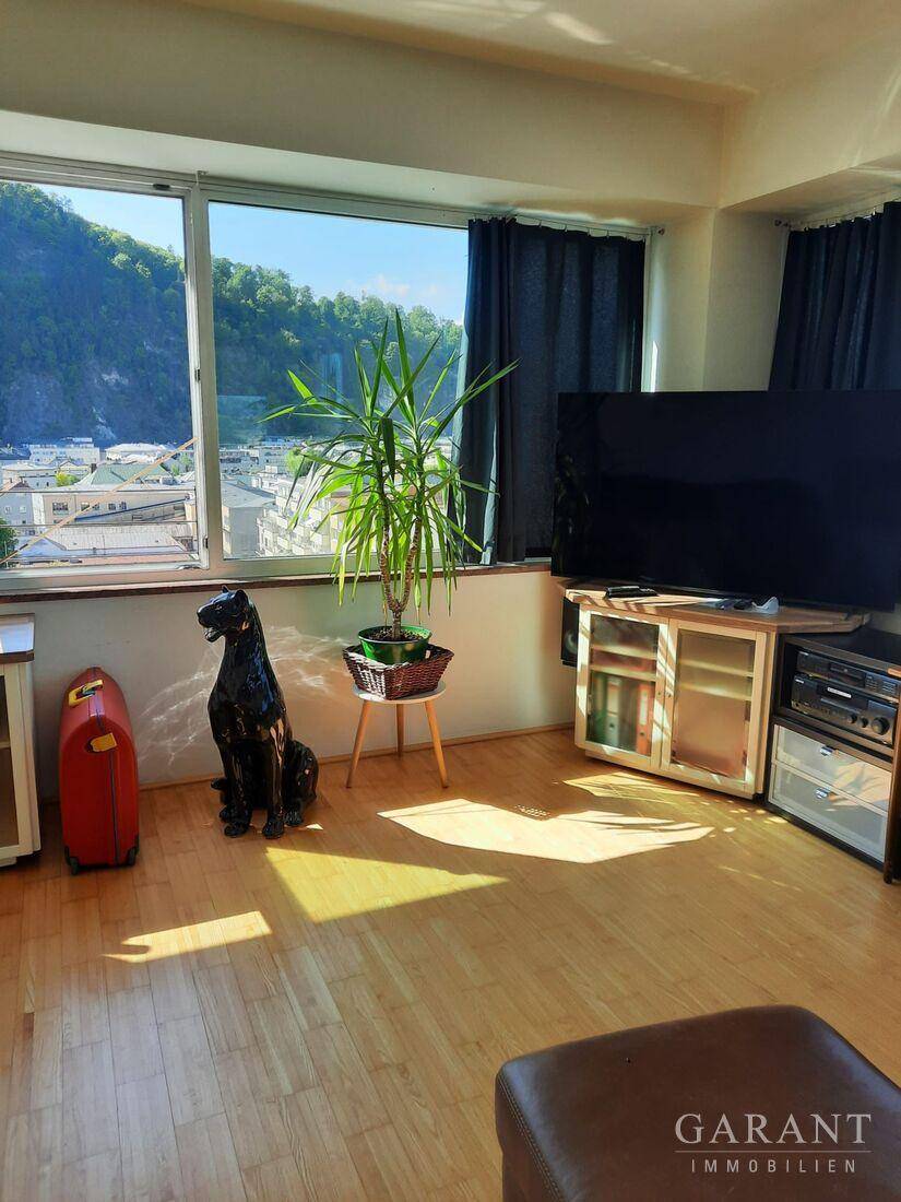 Gemütlicher Wohnbereich mit Fernseher und großen Fenstern, die einen Panoramablick ermöglichen.
