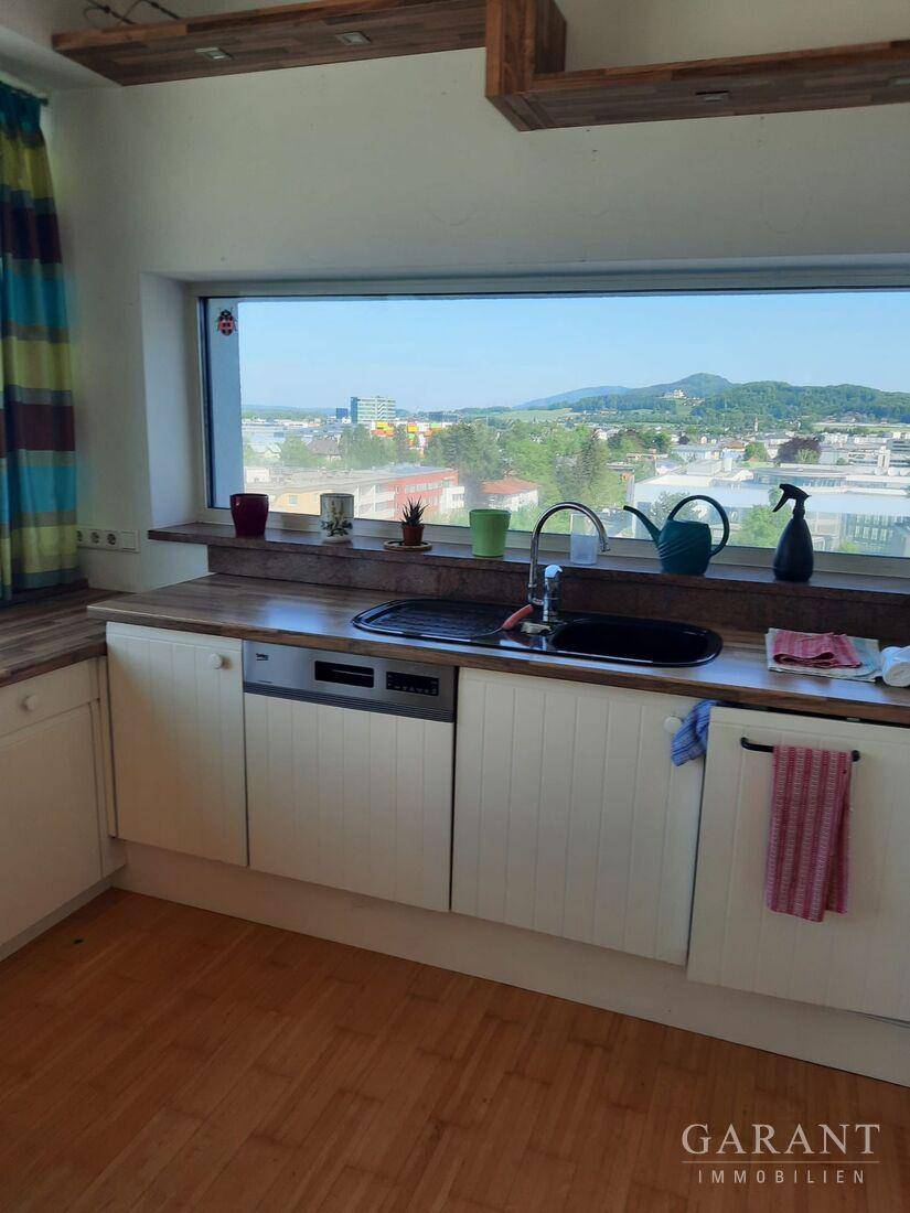 Funktionale Küche mit Spülmaschine und breitem Fenster, das einen weiten Stadtblick bietet.