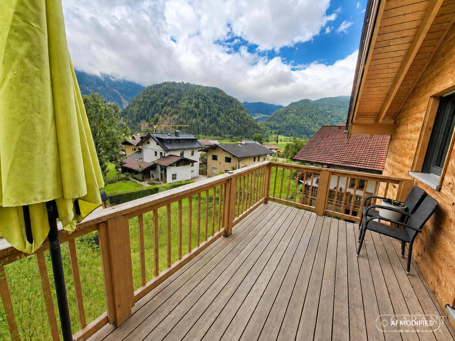 Geräumiger Holzbalkon mit Sitzgelegenheiten und weitem Blick auf die grüne Berglandschaft.