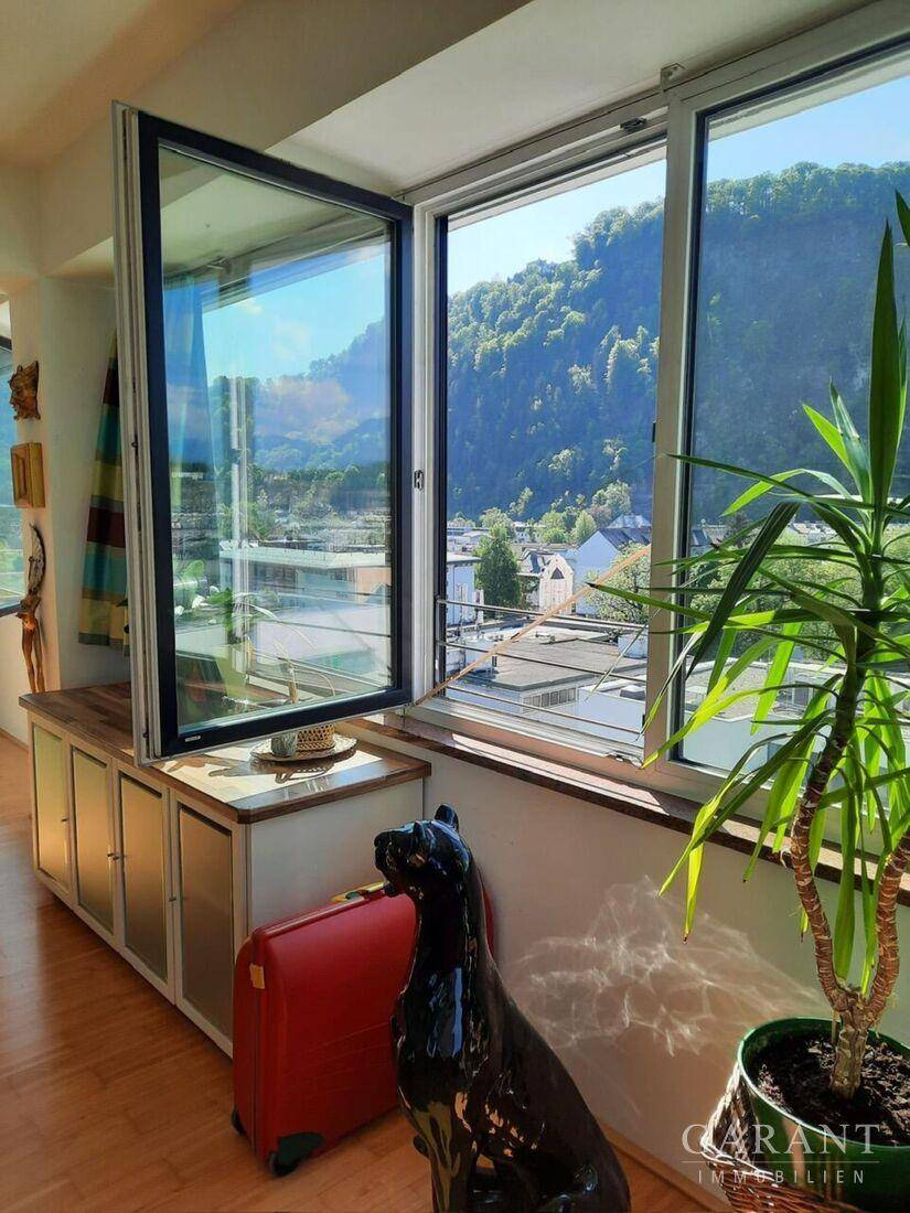 Lichtdurchfluteter Wohnbereich mit weitem Blick auf die umliegende Berglandschaft und die Stadt.