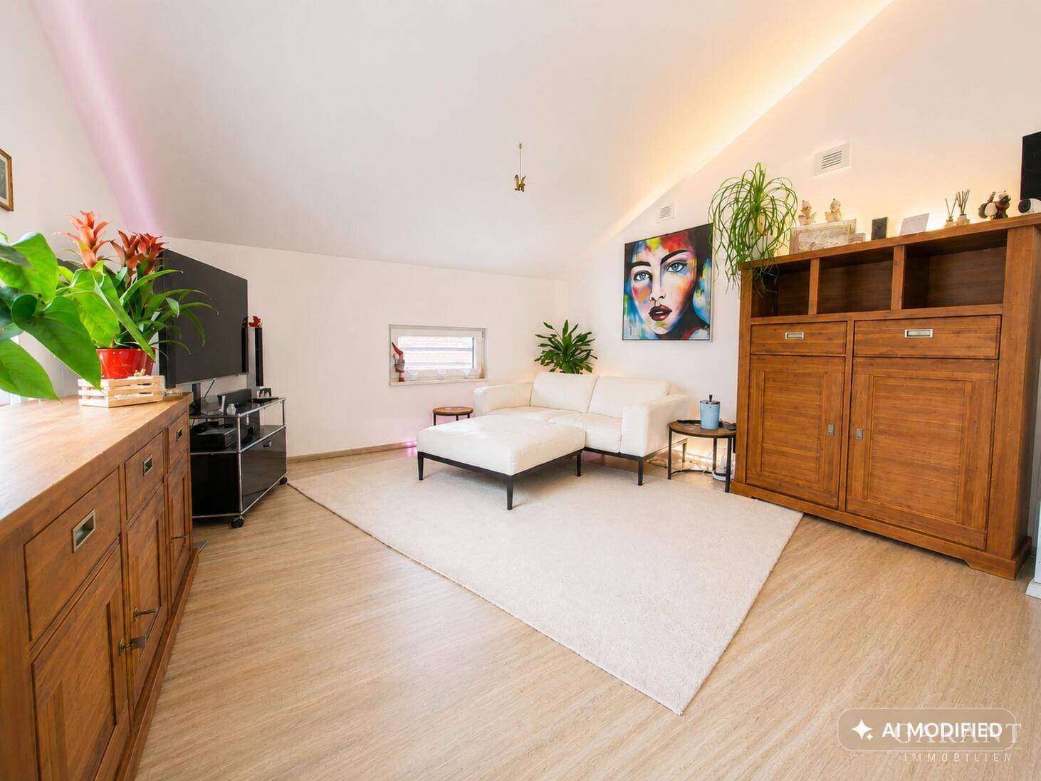 Helles Wohnzimmer im Dachgeschoss mit schrägen Wänden, modernem Sofa und Holzboden.