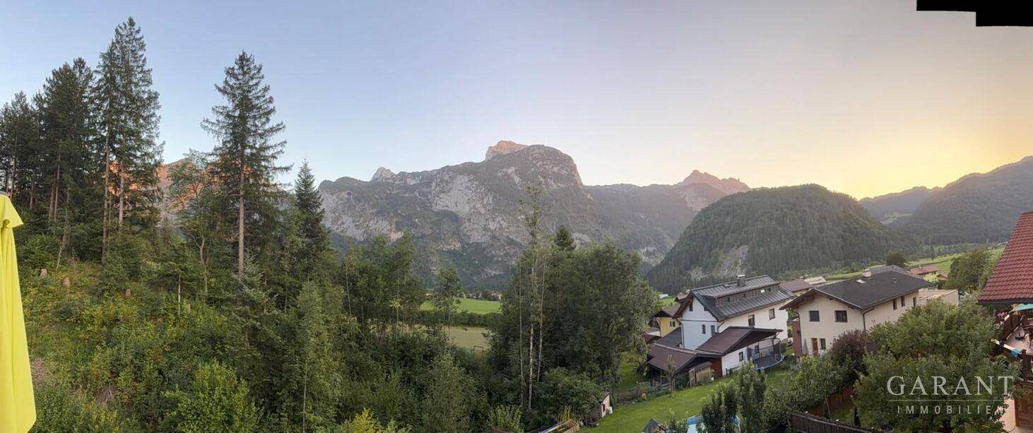 Panoramablick auf die umliegende Berglandschaft und die ländliche Siedlung bei Sonnenuntergang.